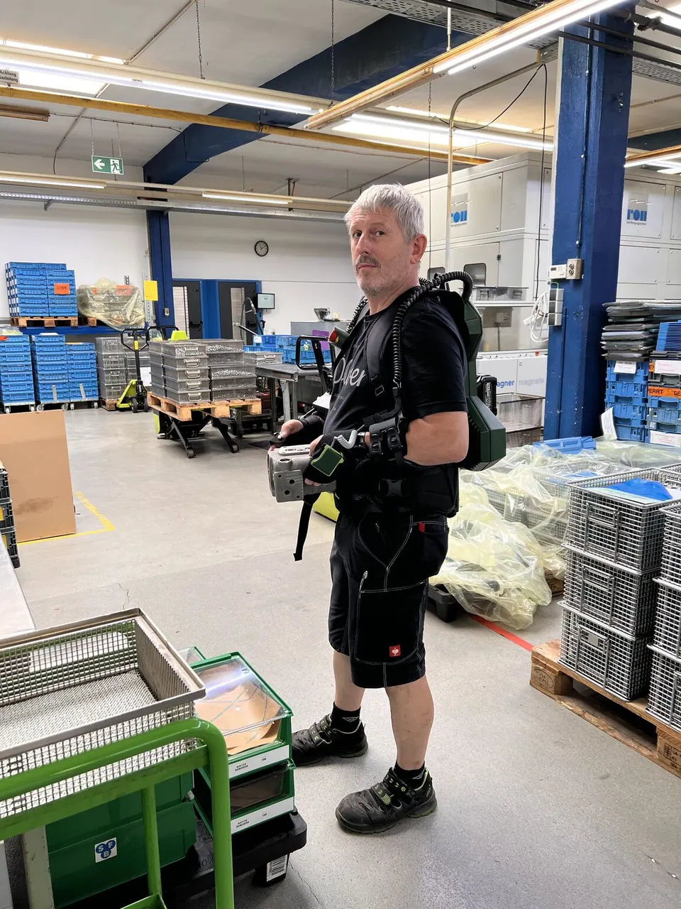 Ein Mitarbeiter von SFB testet das EASE Exoskelett im Produktionsalltag.